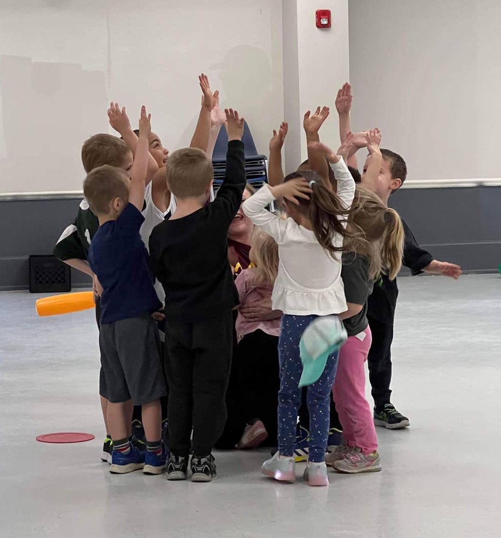 A group of preschoolers with their hands up